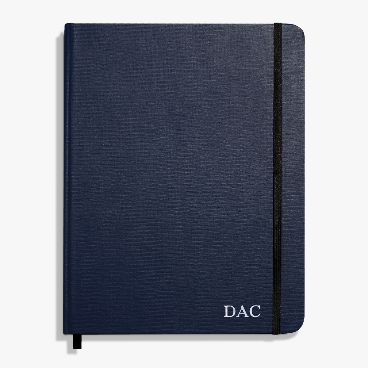 A sleek notebook with a black cover and an elastic band, embossed with the initials "DAC" on the front