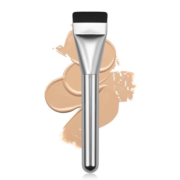 Makeup brush with a metallic handle against a background of beige foundation swatches