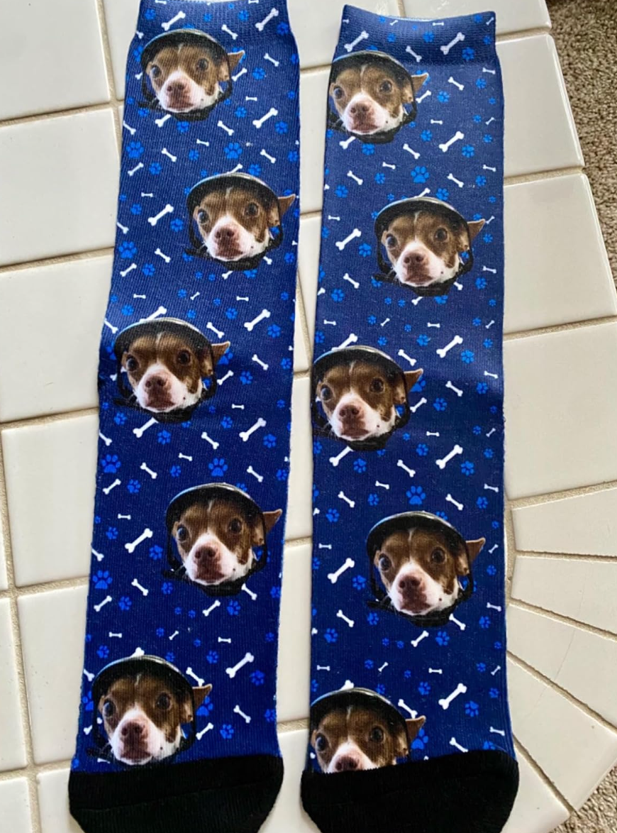 Socks featuring a pattern of dog faces and bones on a patterned background, laid on a tiled surface