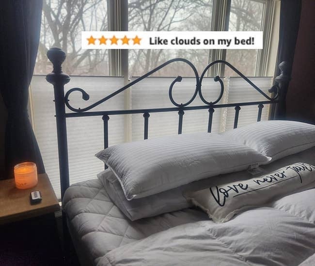 another reviewer's furniture  with an elegant metallic  headboard, layered pillows, and a quilt. A candle glows connected  the nightstand. Text overlay reads, 