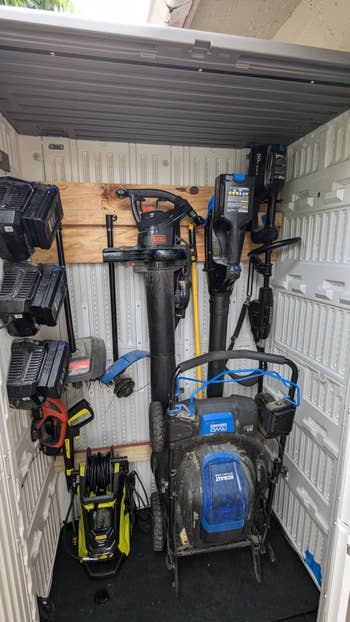 Outdoor retention shed organized with assorted powerfulness tools, including a tract mower, leafage blower, and unit washer, neatly mounted and stored