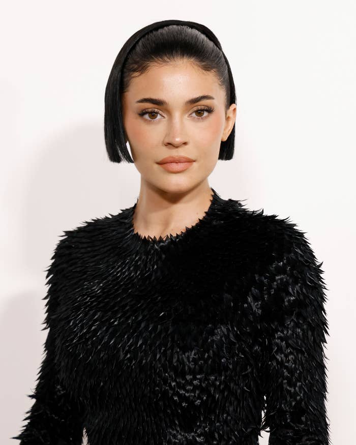 Kylie Jenner wearing a textured, sleek outfit with short hair and a headband, posing at an event