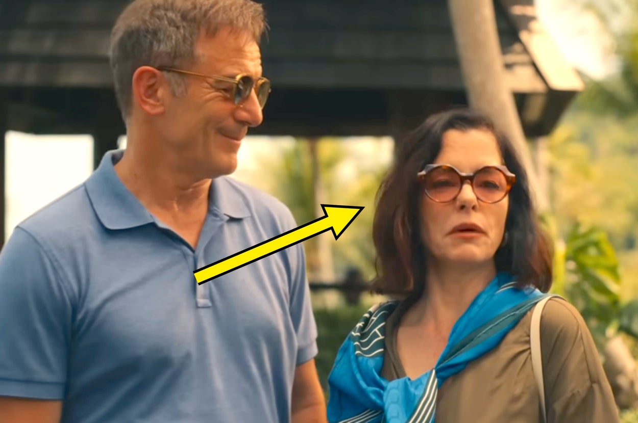 Two individuals outdoors, both wearing sunglasses. The man is in a polo shirt, and the woman is in a flowing blouse with a scarf