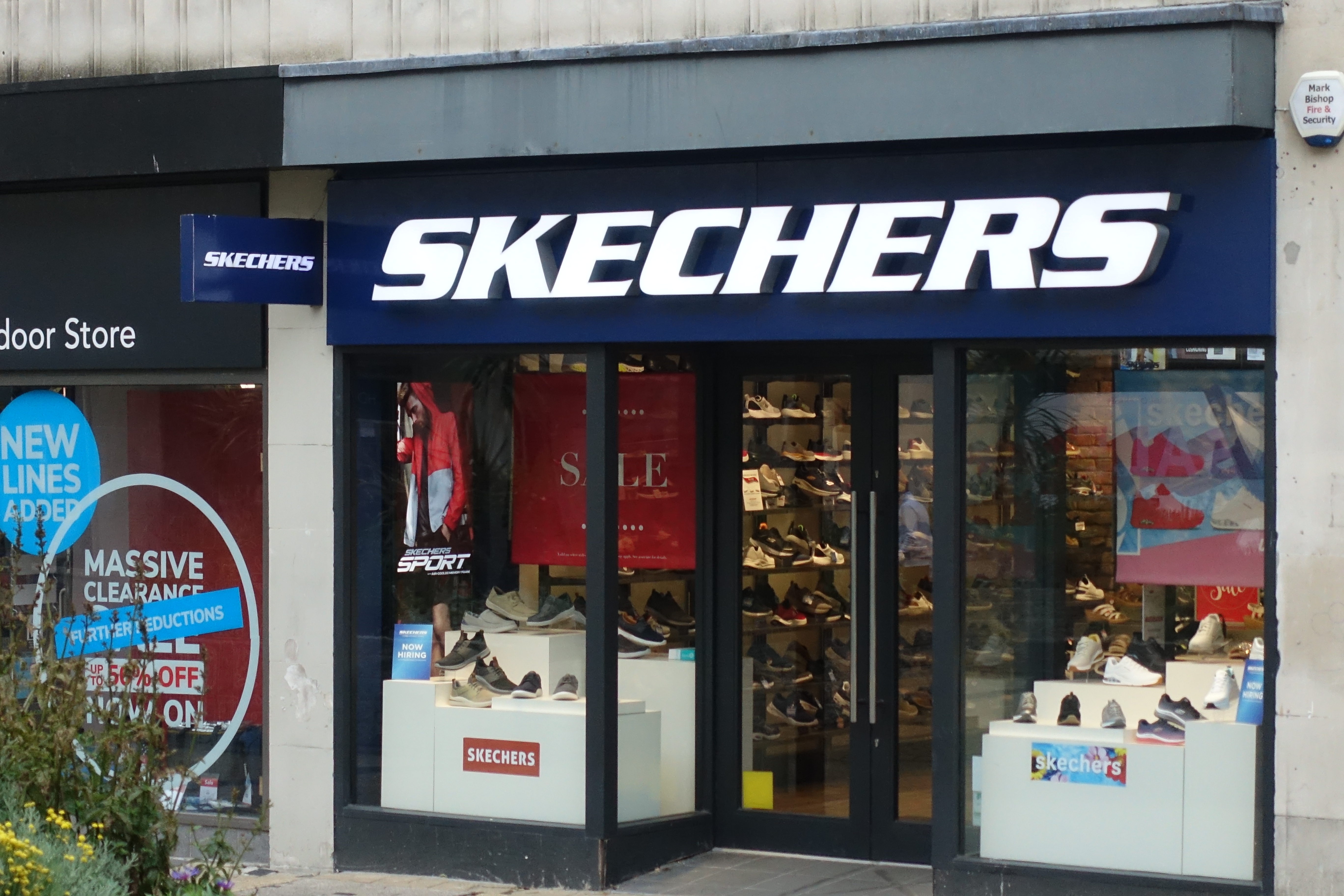 Skechers Storefront med skomoster, salgsskilt og plakater i vinduene. Salgsmeldinger kan sees i bakgrunnen