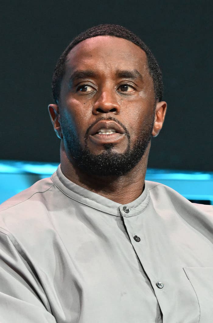 Diddy in a light-colored buttoned shirt is looking slightly to the side