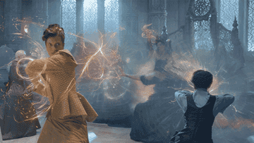 In a scene from &quot;The Wheel of TIme,&quot; a woman in a golden dress shoots a magical fireball at another character.