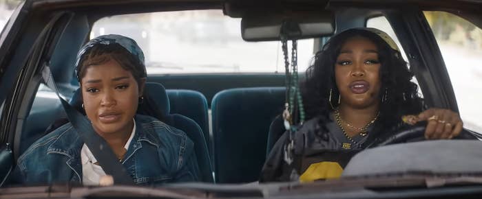 Keke Palmer and SZA sitting in a car; the driver wears a black hat and casual attire, the passenger has a denim jacket and headscarf