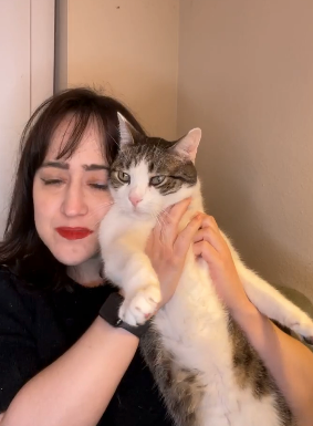 adult mara holding a relaxed cat close, both appearing content