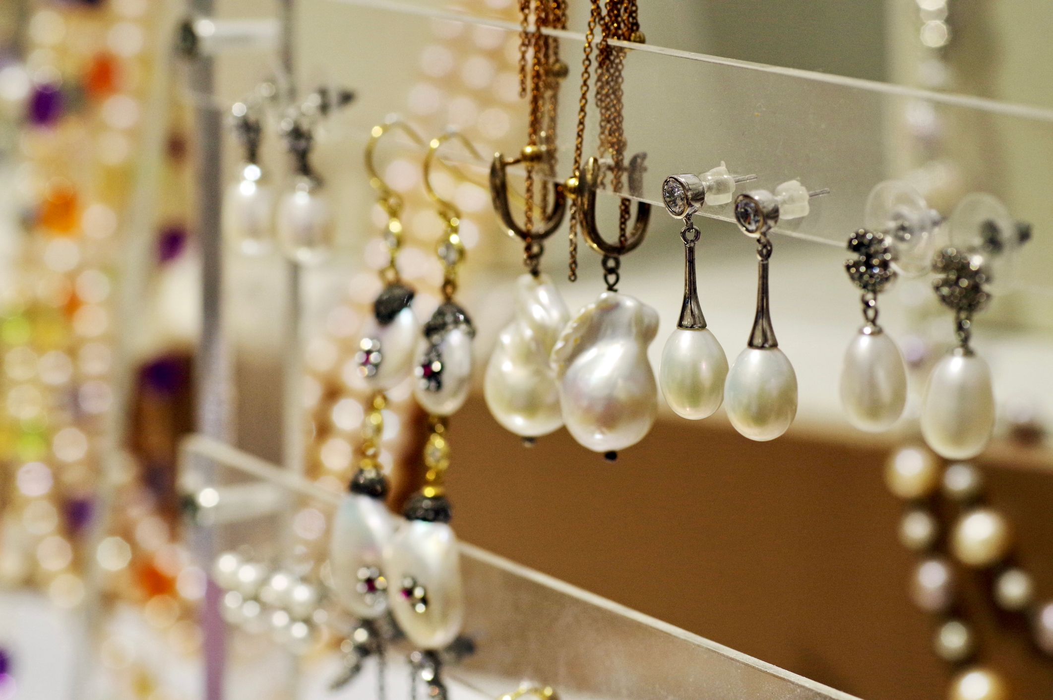 Display of pearl earrings and necklaces on a clear stand, showcasing a variety of elegant designs