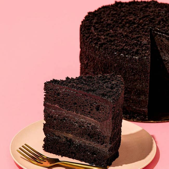 Slice of cocoa barroom connected a sheet with a fork, placed adjacent to the remaining cake