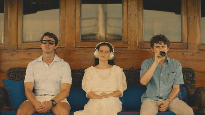 Patrick Schwarzenegger, Sarah Catherine Hook, and Sam Nivola sitting on a boat as Saxon, Piper, and Lochlan on The White Lotus