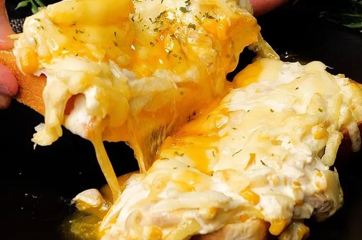 チーズがとろけたホットサンドを手で持っている様子。チーズがたっぷりとのっている。