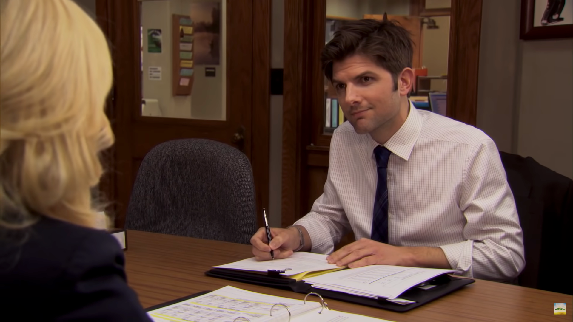 Adam Scott as Ben Wyatt on "Parks and Rec" sat at a desk