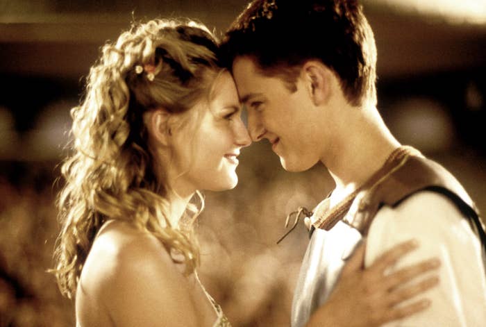 A romantic scene with two people gently touching foreheads, smiling at each other, surrounded by a softly blurred background