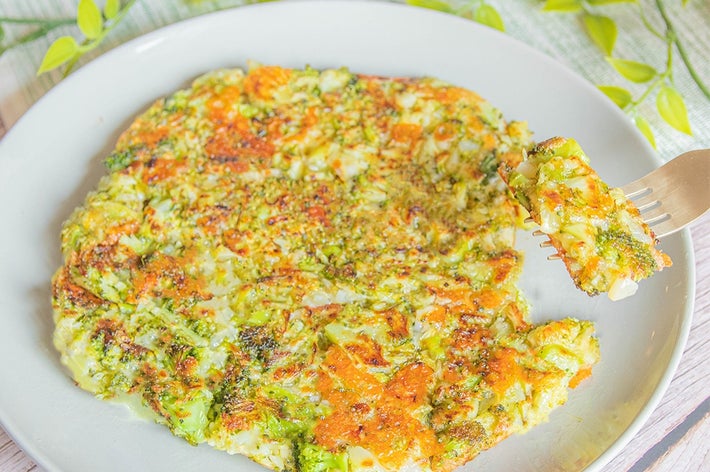 陶器の皿に盛られたブロッコリーとチーズ料理のクローズアップ。フォークで一口分が持ち上げられている。