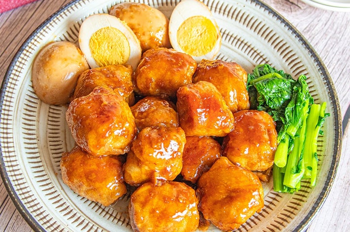 皿に盛られた角煮、ゆで卵、青菜の料理。木のテーブルに置かれている。