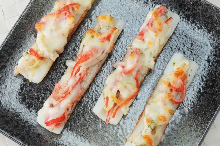 プレート上の4本のカニカマスティックに、野菜と溶けたチーズがトッピングされています。