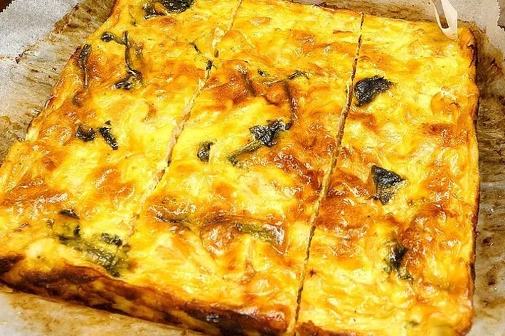 焼かれたキッシュがオーブン用紙にのせられて切り分けられている。