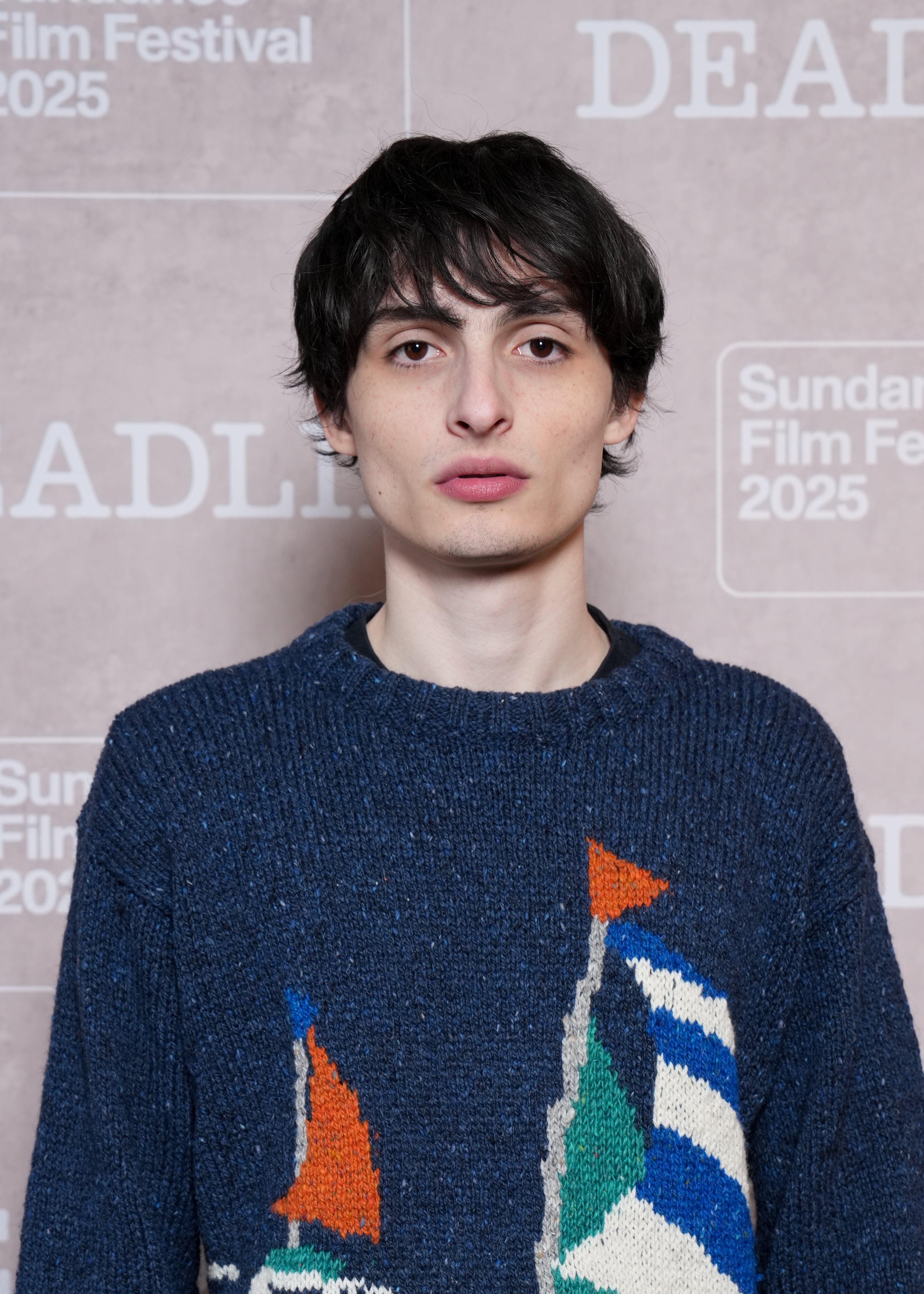 Person at Sundance Film Festival 2025 in a textured sweater with abstract patterns, standing against a backdrop with event text
