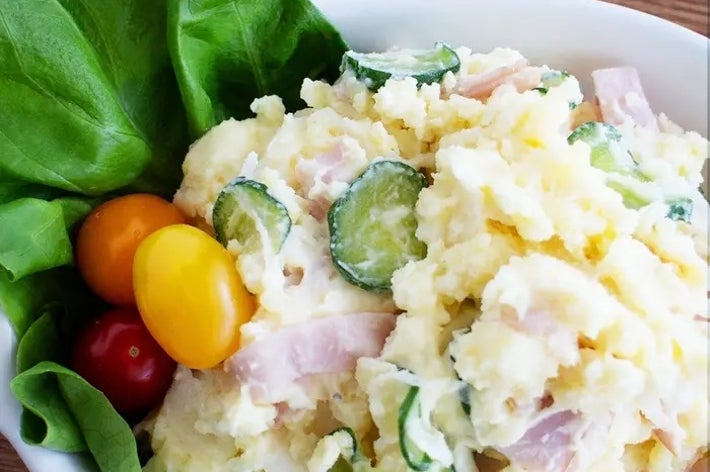 サラダボウルにポテトサラダ。トマト、きゅうり、レタスが添えられている。