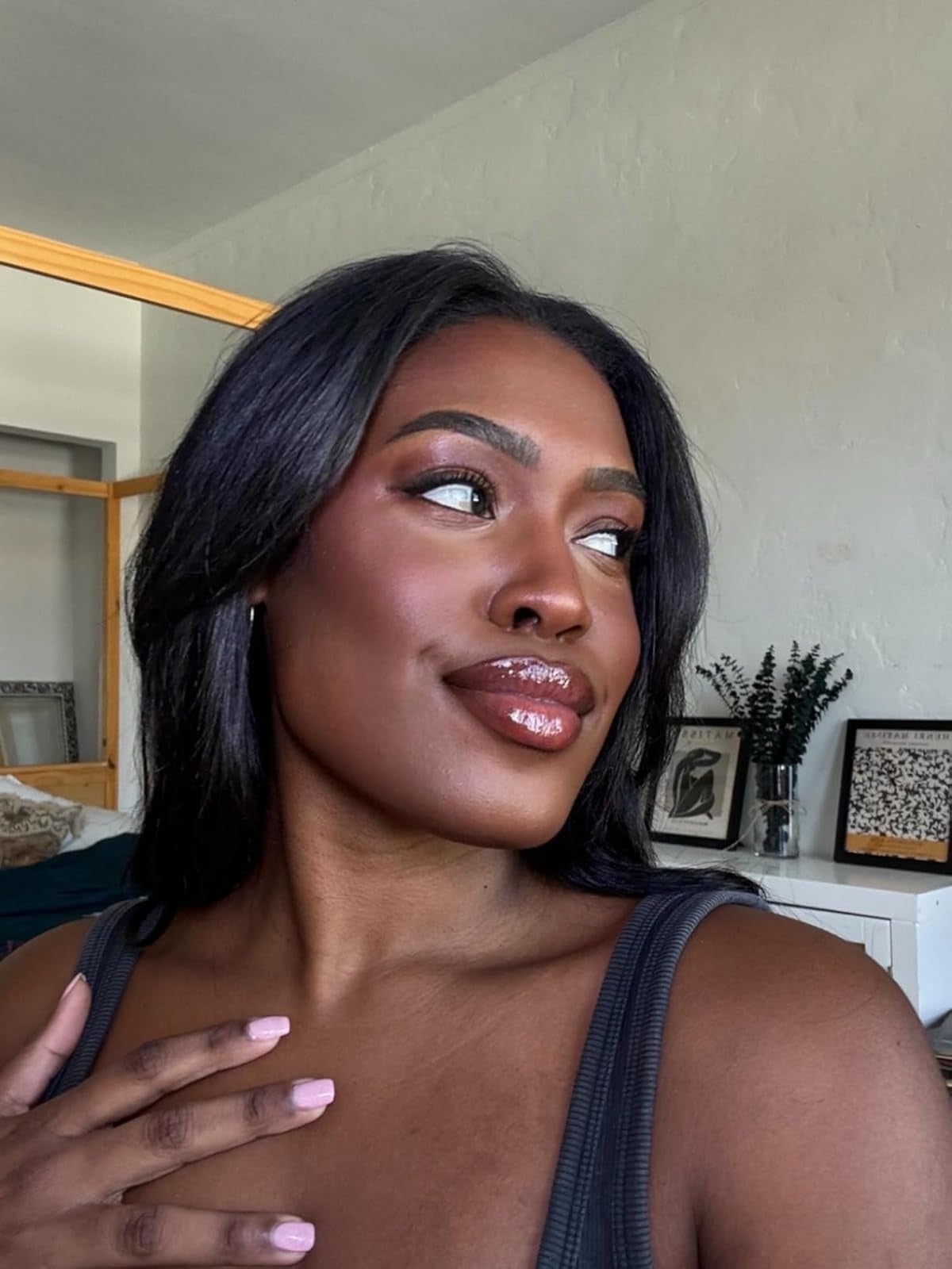 Person smiling successful  a country   with framed creation  connected  the wall, wearing a sleeveless apical  and glossy makeup