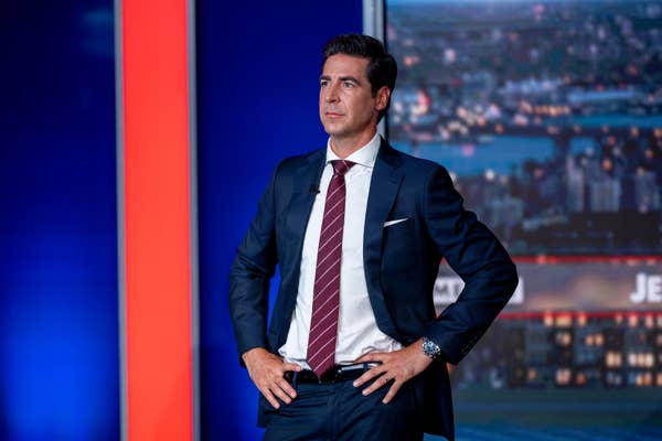 Person in a dark suit and striped tie stands confidently with hands on hips, set against a cityscape backdrop on a news set