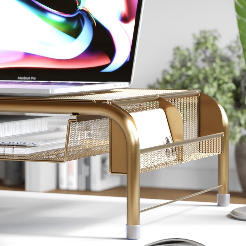 Laptop on a stylish, gold mesh desk organizer with a document holder, against a blurred plant background. Perfect for organizing office space