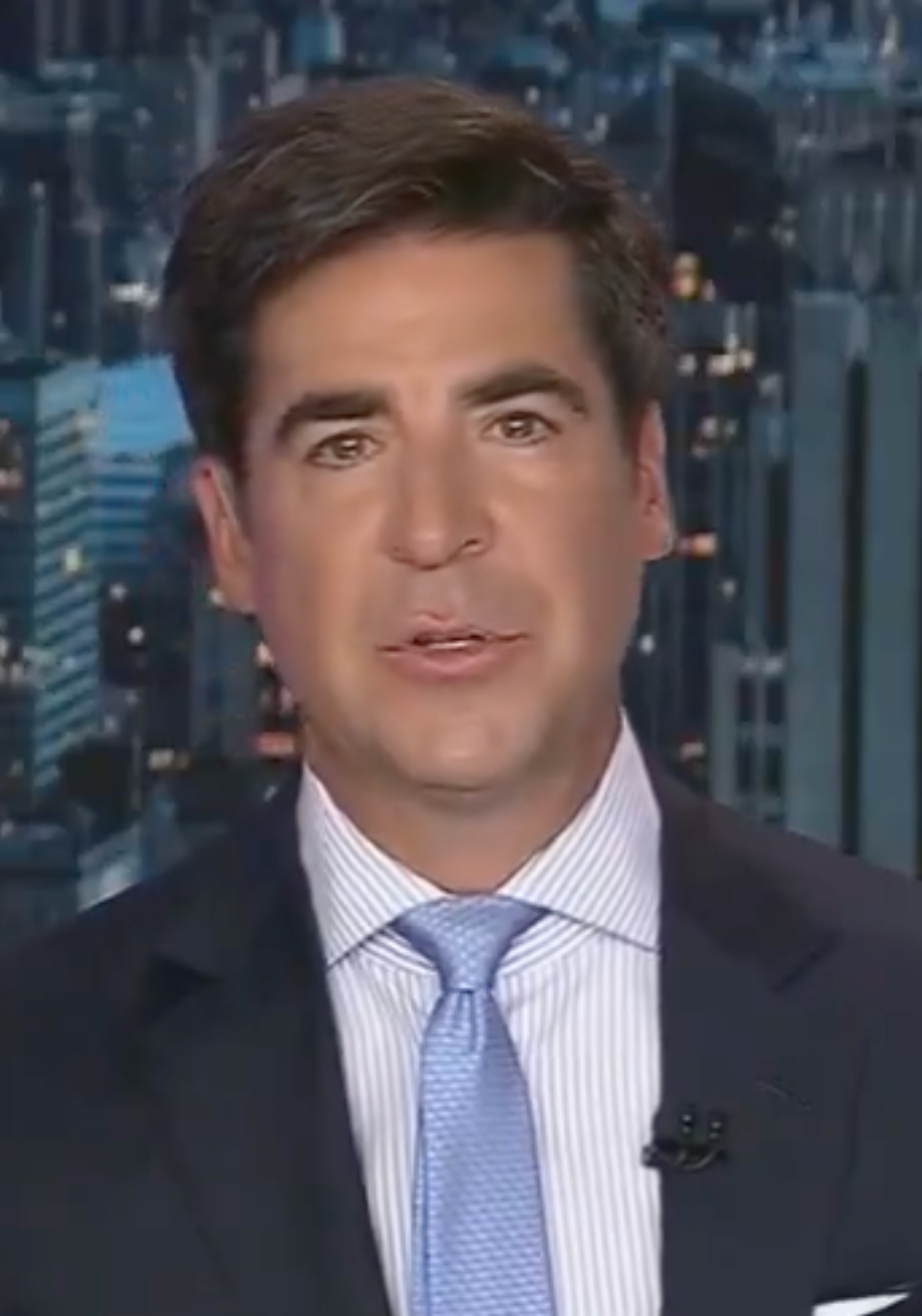 A person in a suit and tie is speaking against a cityscape backdrop