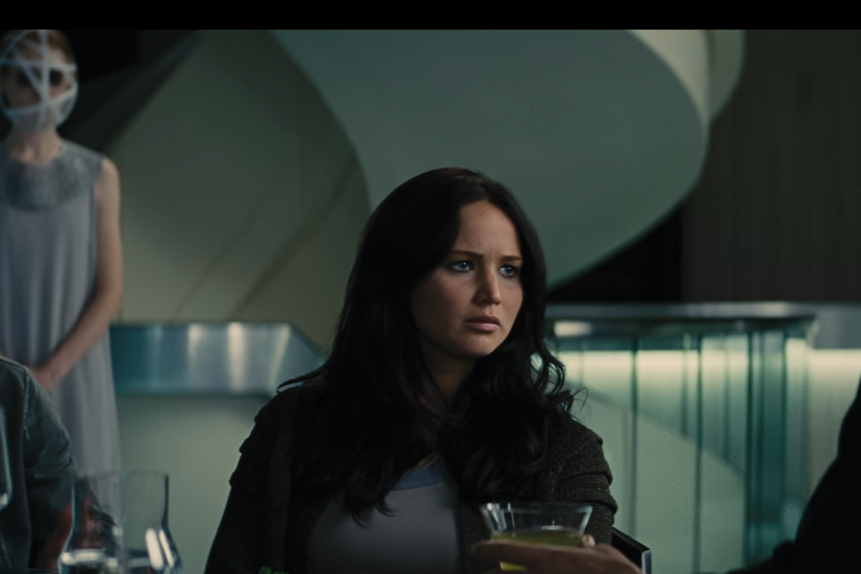 Peeta and Katniss sitting at a table in a movie scene