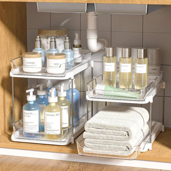 Bathroom furniture with organized skincare products, lotions, jars, and neatly folded towels connected a tiered support nether a sink