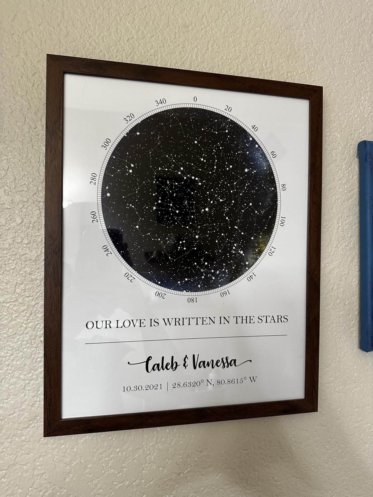 Framed star map titled "OUR LOVE IS WRITTEN IN THE STARS" with names Caleb & Vanessa, date 10.30.2021, and coordinates below