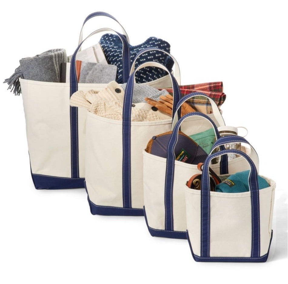 Four canvas tote bags in varying sizes are filled with folded clothes and accessories, showcasing storage versatility