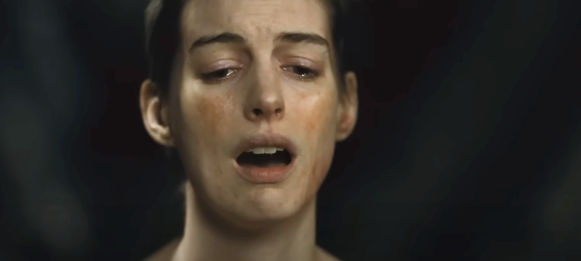 A person appears emotional, with a pained expression, mouth slightly open, and teary eyes, conveying intense drama or distress