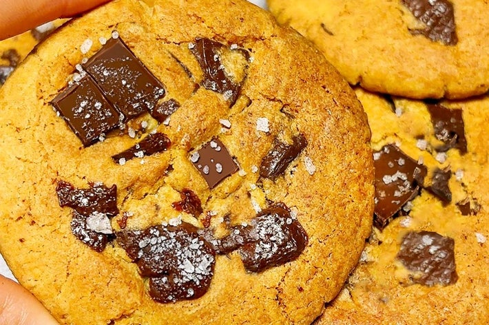 チョコレートチャンクがちりばめられたクッキーを手に持つ。クッキーの上に塩が振りかけられている。