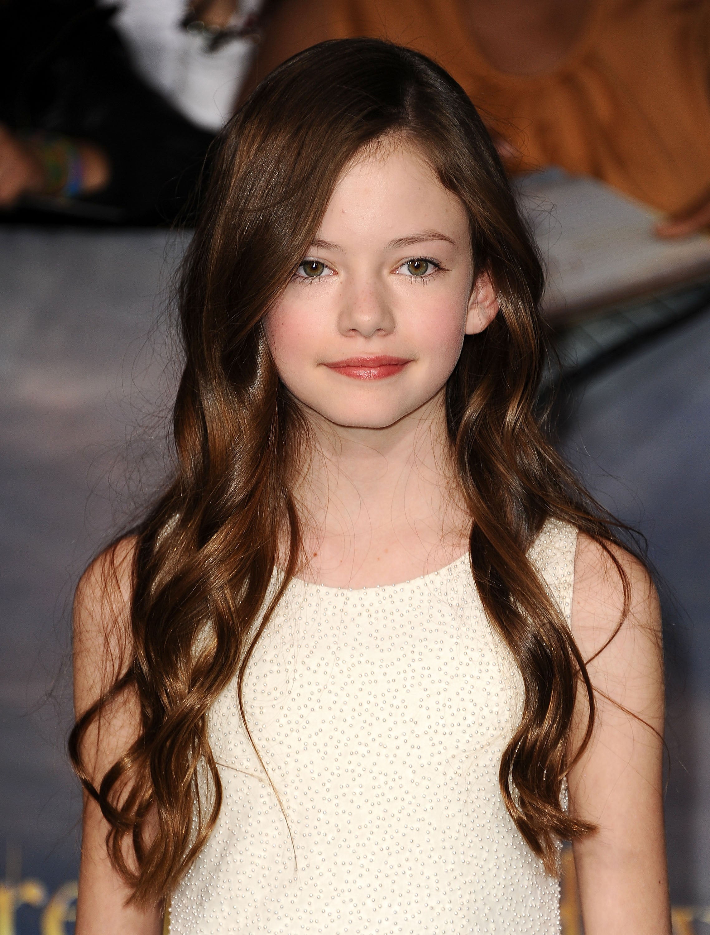 Young girl with long wavy hair in a textured sleeveless dress at a celebrity event