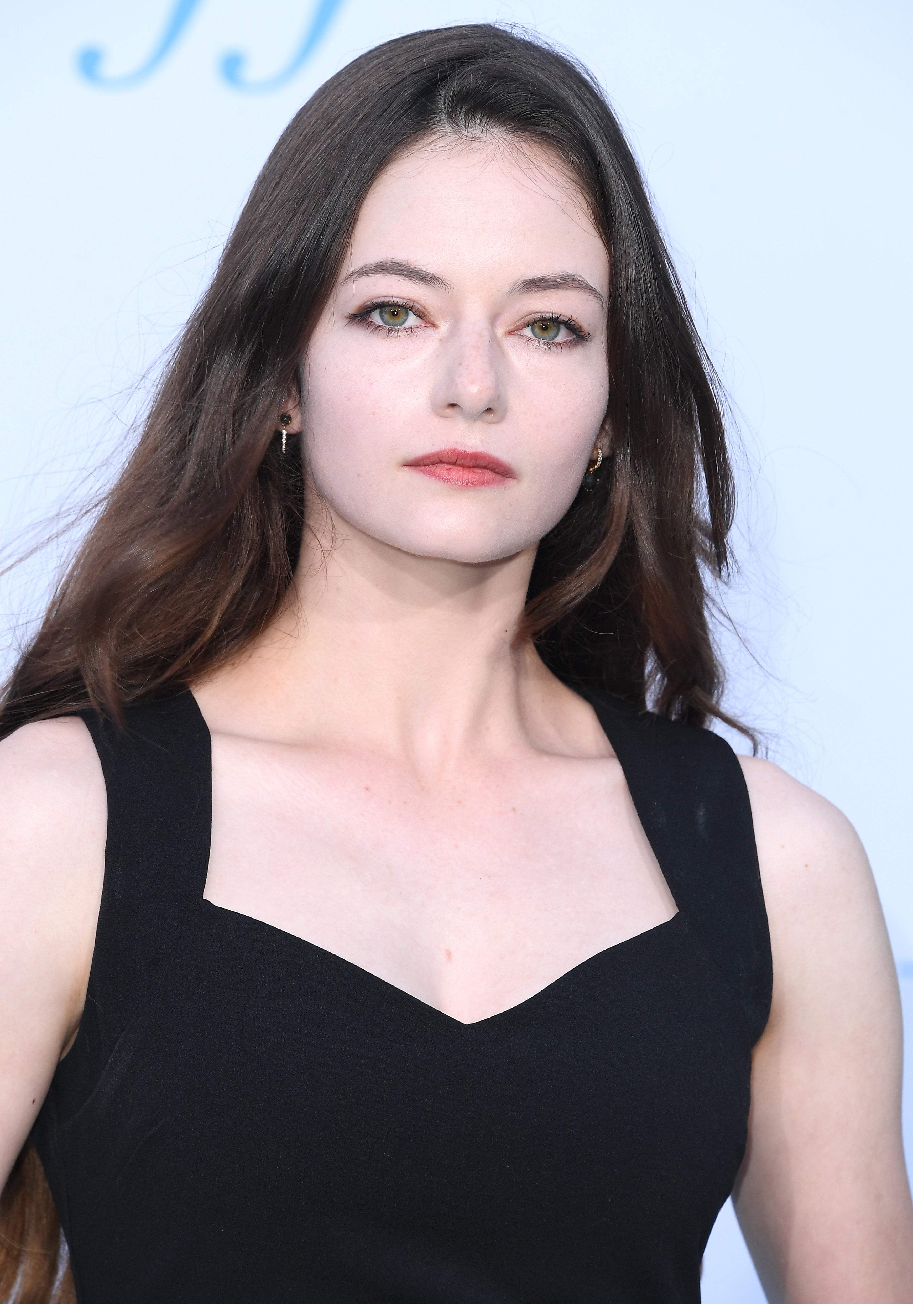 Person with long hair in elegant black dress with a square neckline, attending an event