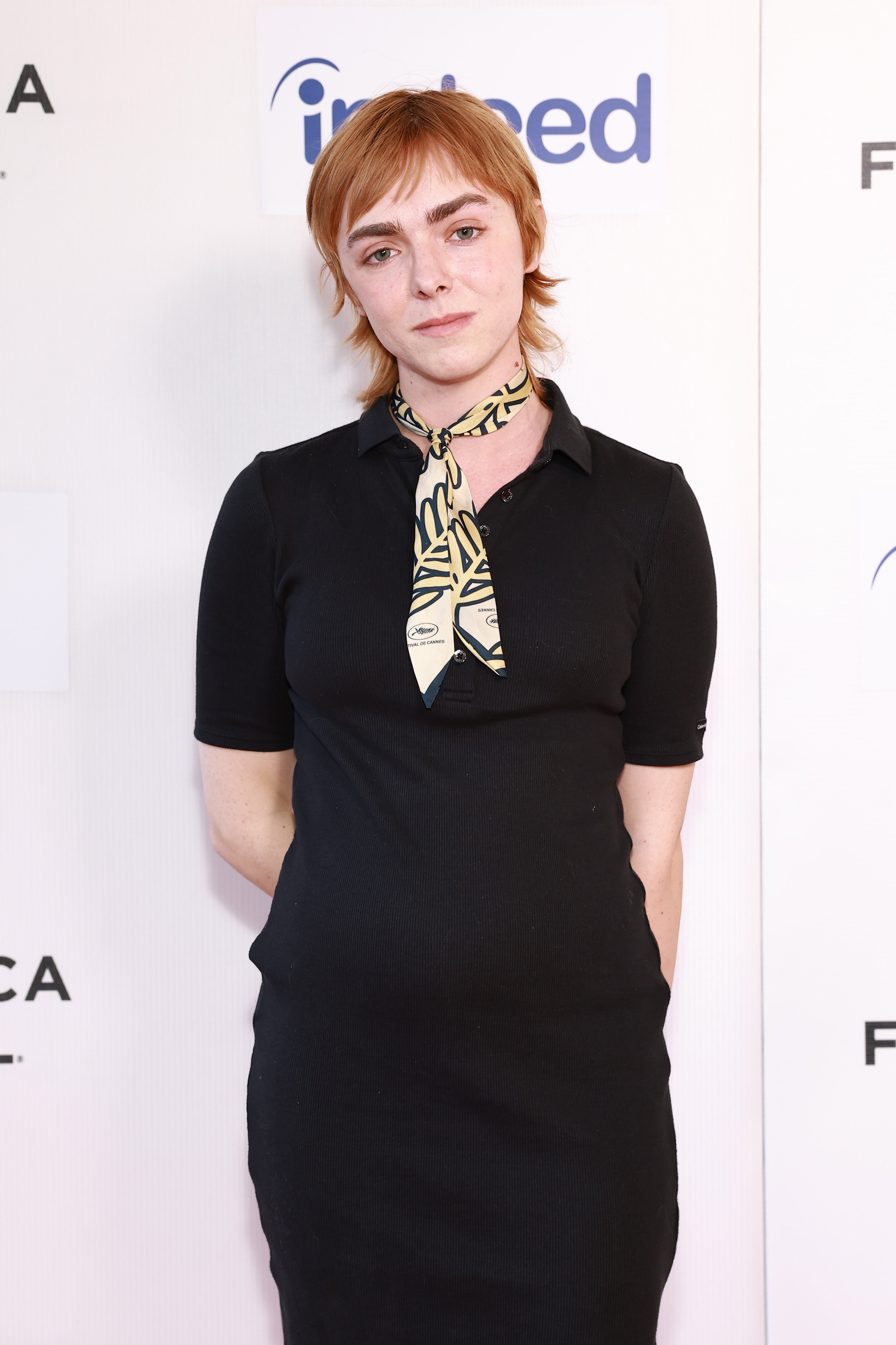 Person in a formal setting wearing a black dress and a patterned neck scarf