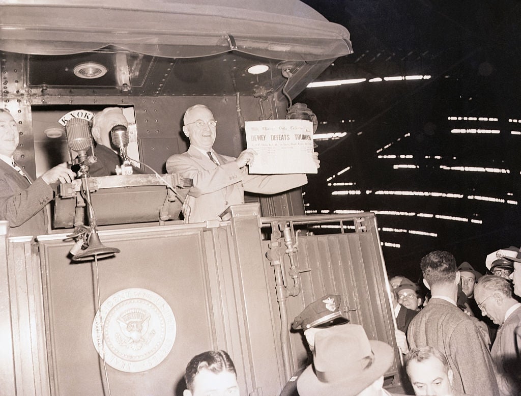 Harry Truman holds up   a paper  with an incorrect header  astir  his defeat, lasting  connected  a bid     platform, surrounded by radical   and microphones