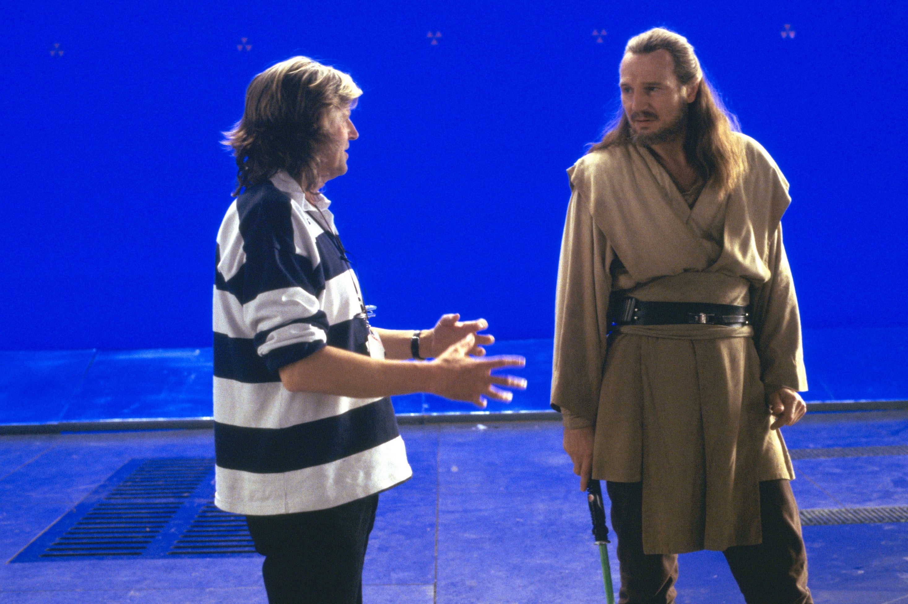 Actor in Jedi costume talks to a director on a film set with blue screen background, likely during the production of a sci-fi movie
