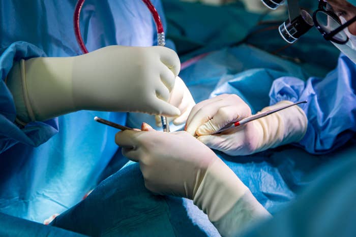 Surgeons in gloves focus on a delicate surgery, working with precision tools and lights over a patient covered in blue drapes