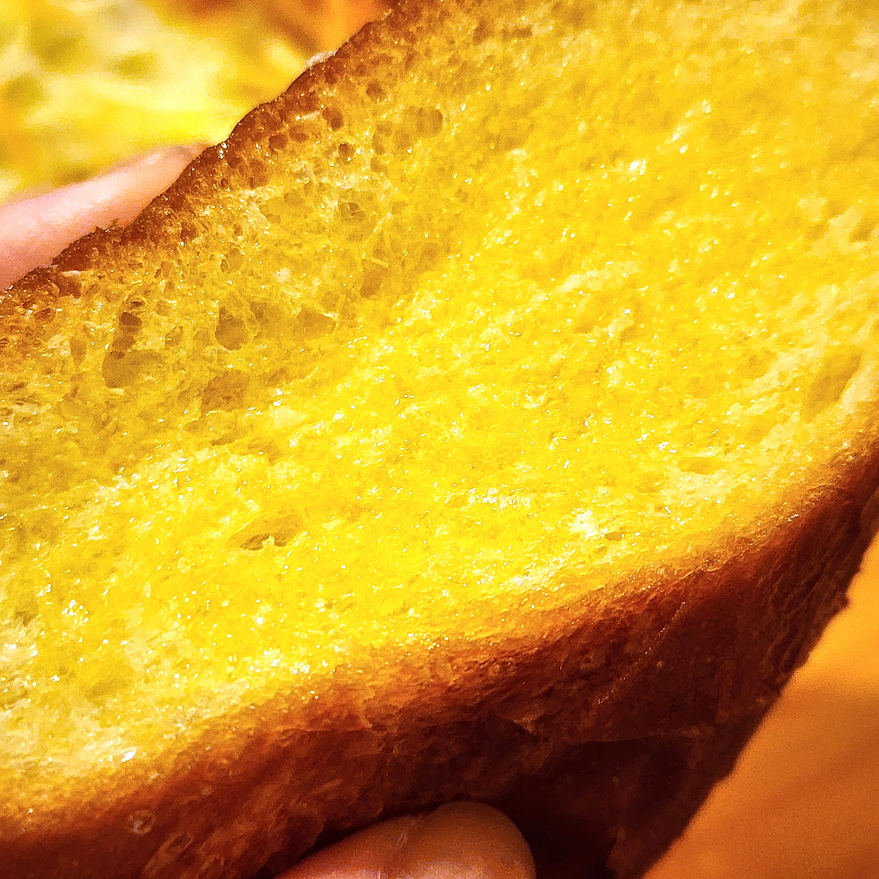 手で持った厚切りのパン。サクサクとした質感で美味しそうな焼き色がついている。