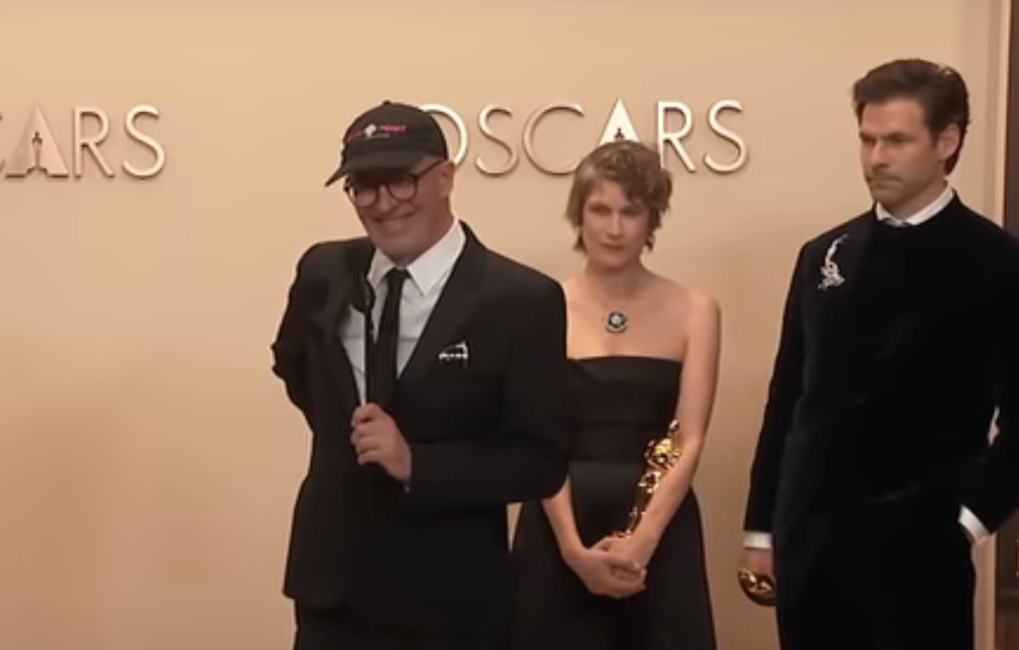 Jacques, wearing a cap, smiles as he speaks into a microphone