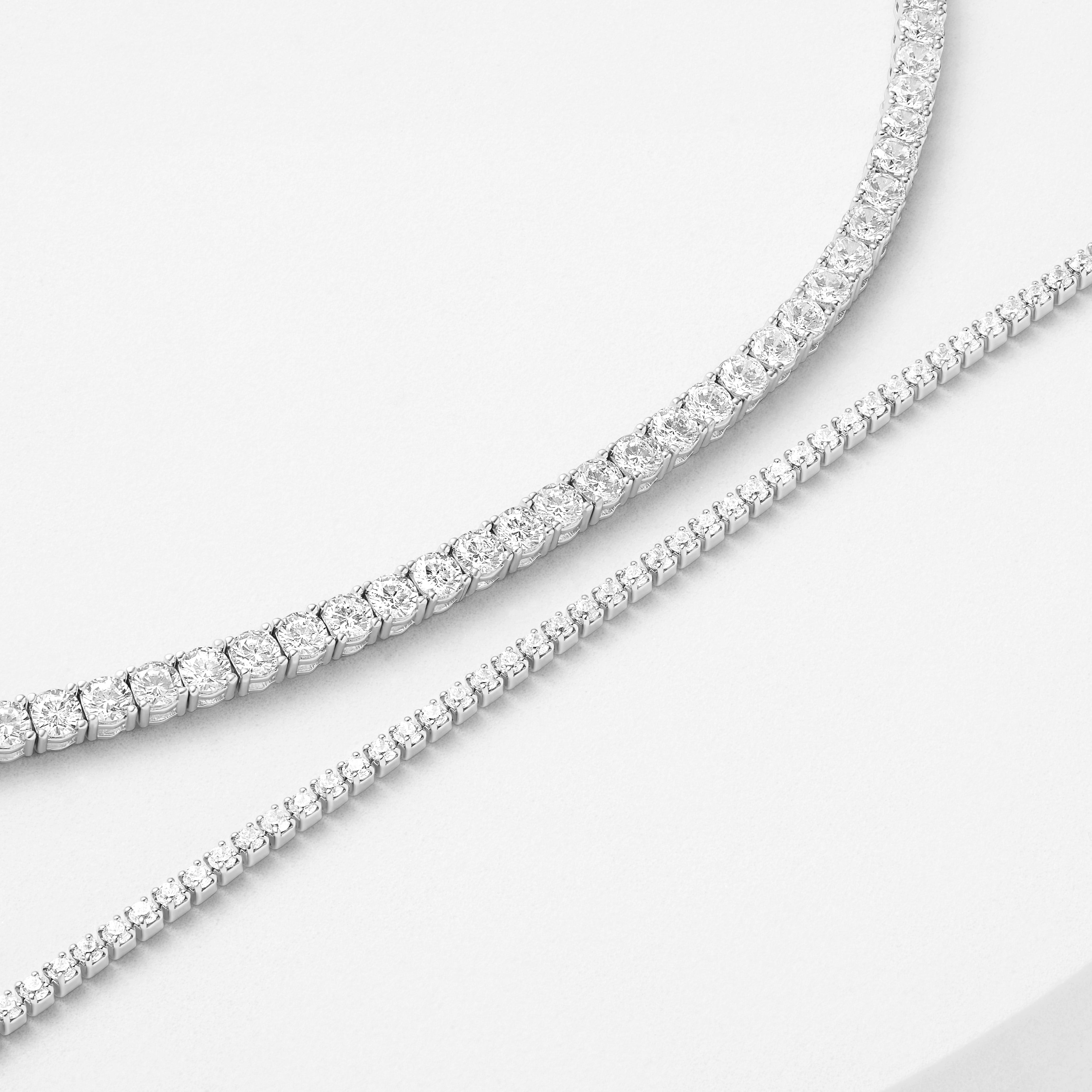 Two elegant tennis bracelets with sparkling details displayed on a white surface