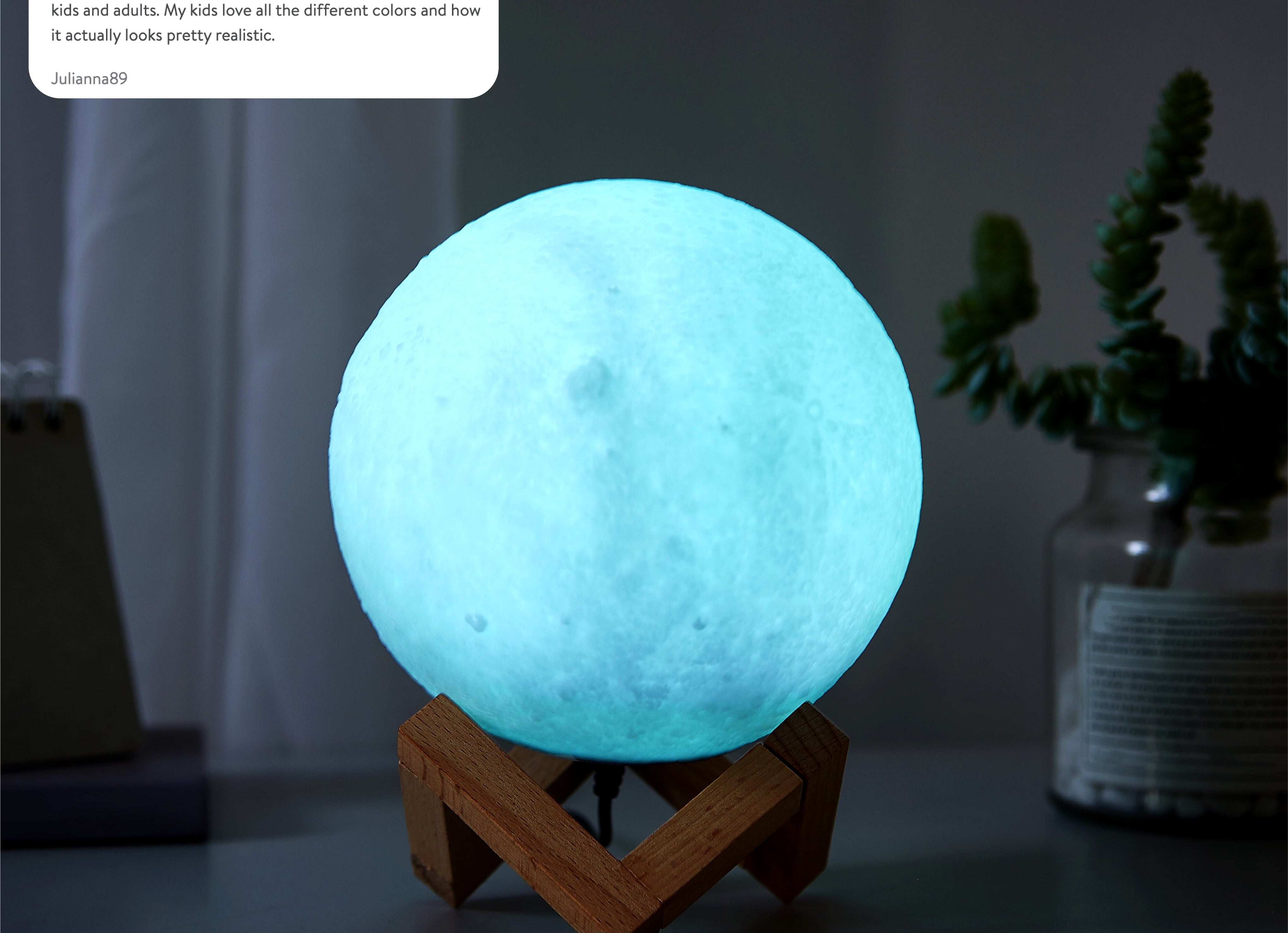 Moon lamp on a wooden stand, with a glowing surface resembling the moon&#x27;s craters