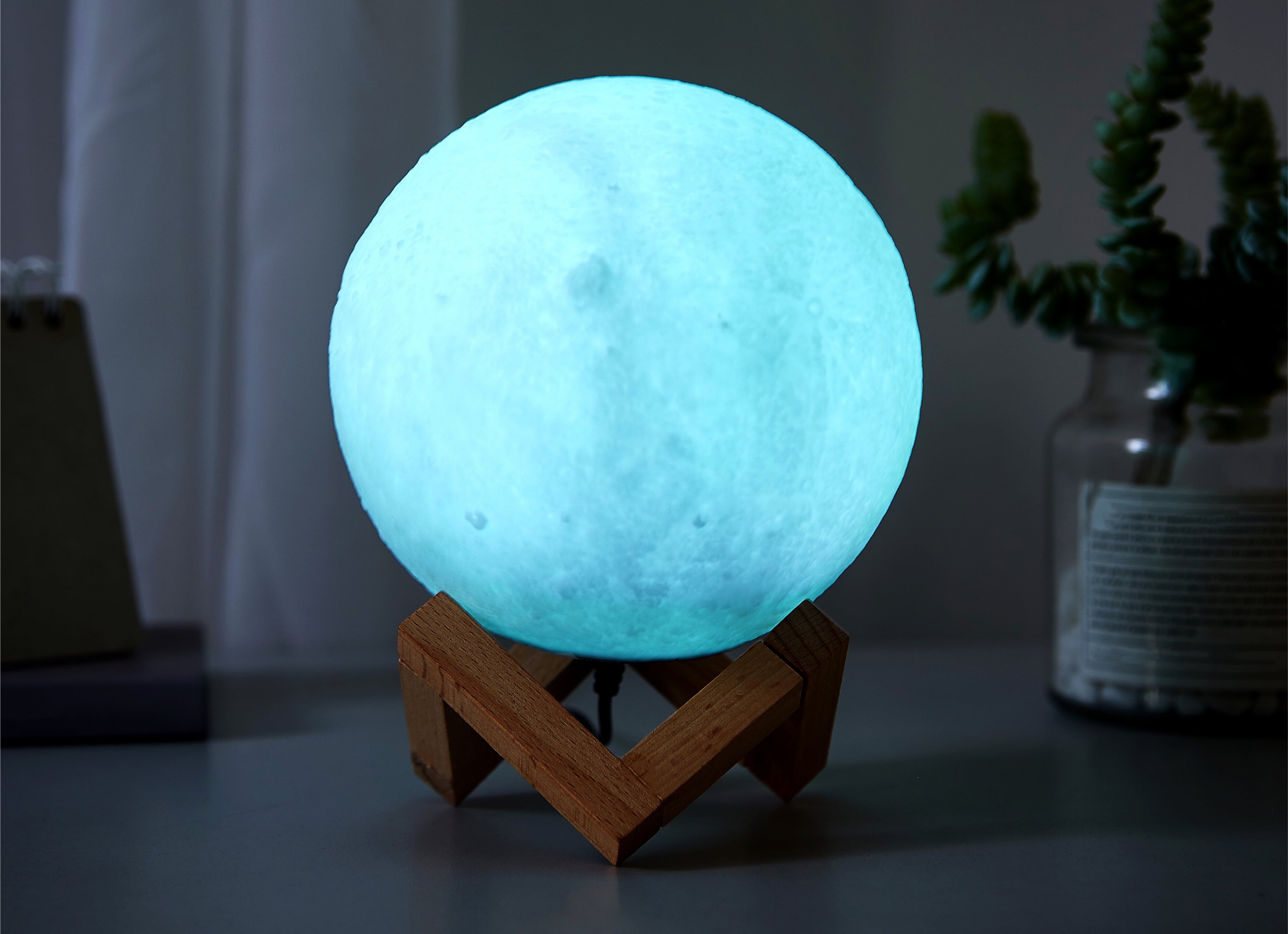 Moon lamp on a wooden stand, with a glowing surface resembling the moon's craters