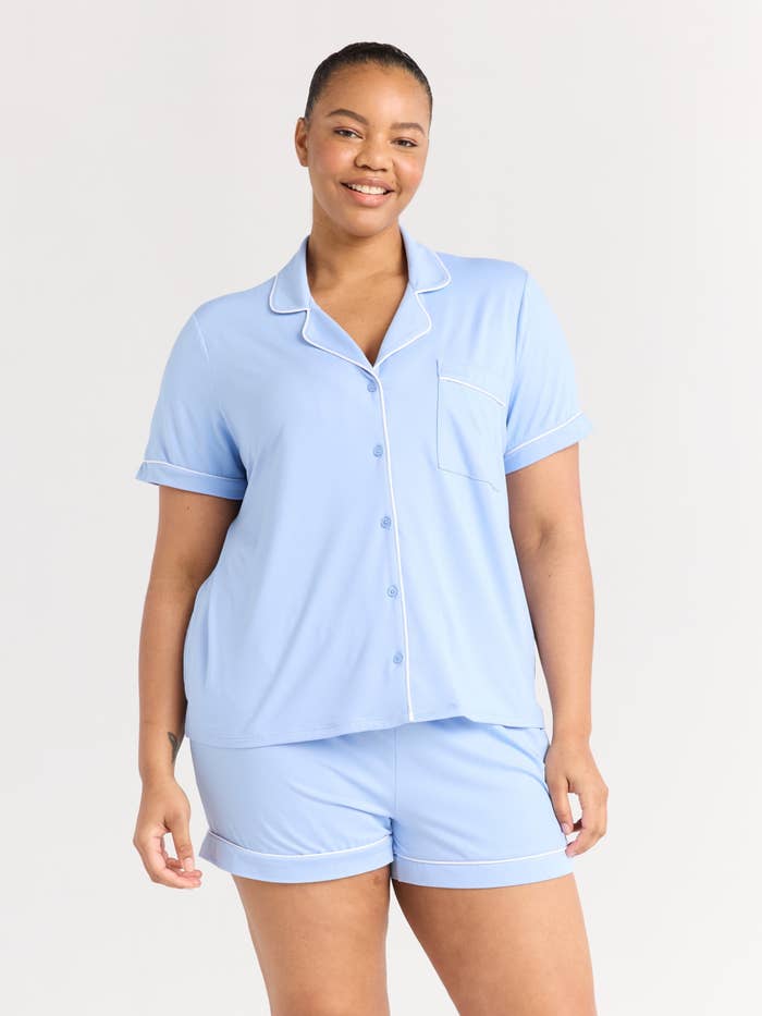 Person smiling in comfortable pajama set with a short-sleeve button-up top and matching shorts
