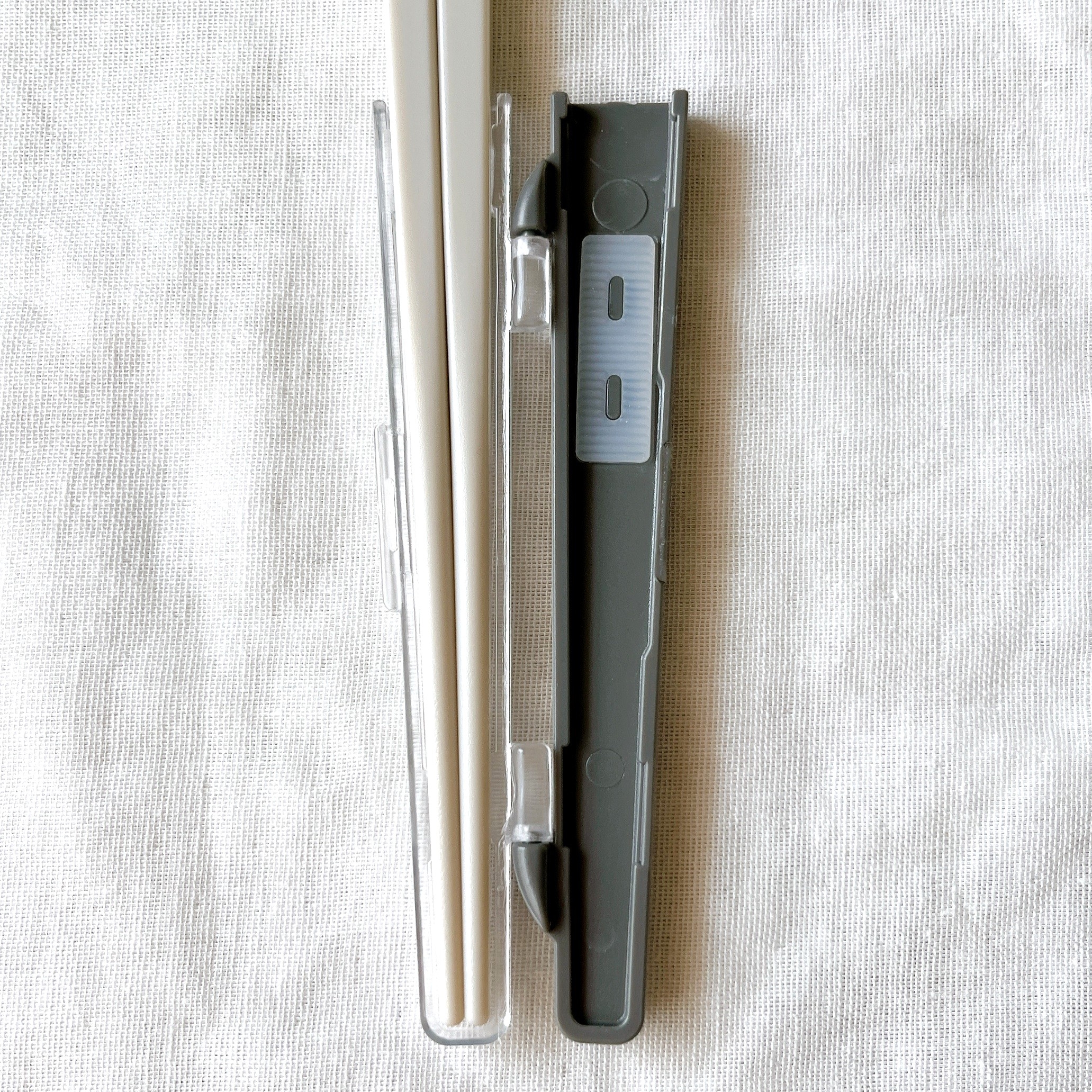 箸とケースのセット。白い箸と黒いケースが布の上に並んでいる。