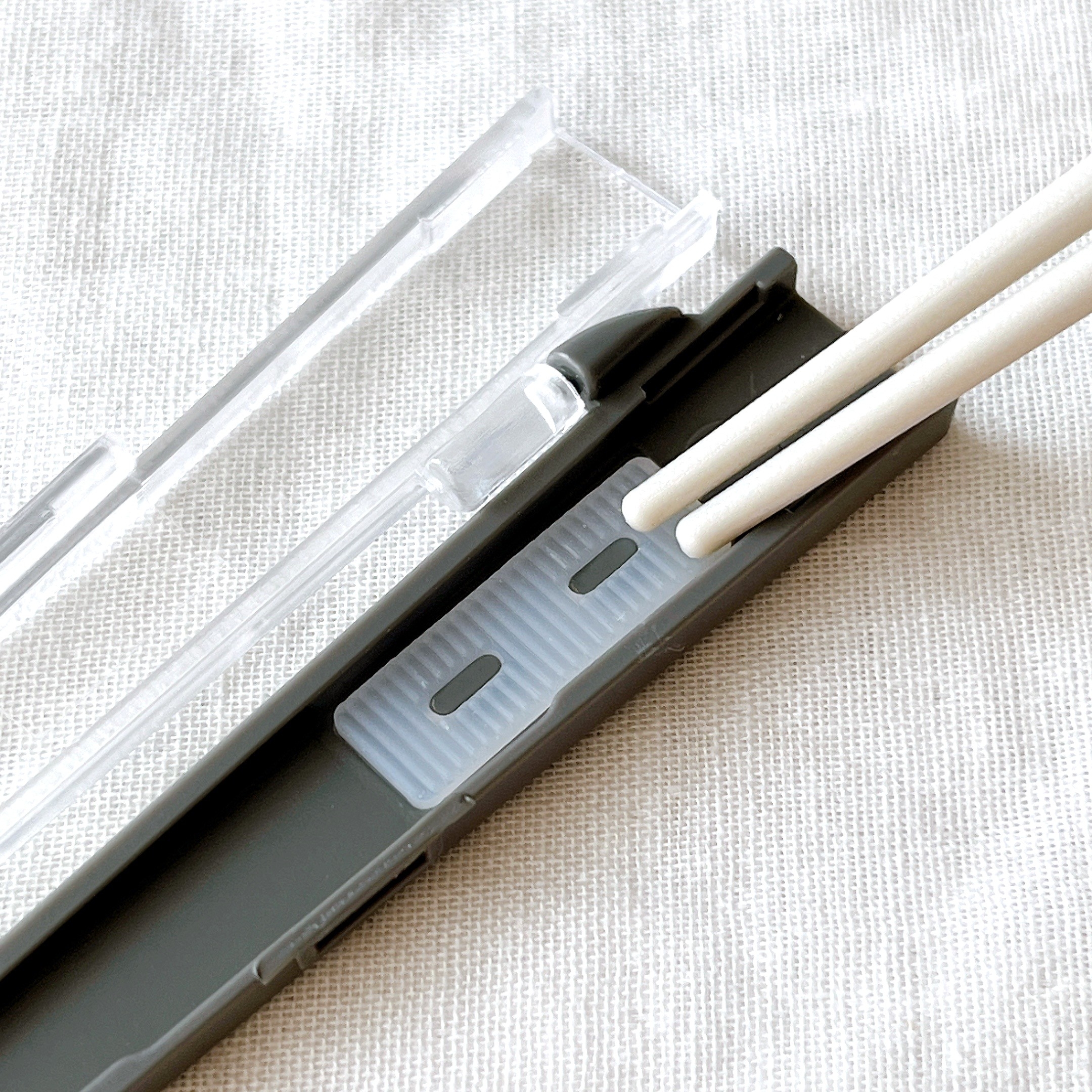 箸ケースに収納された白い箸と透明のカバーの画像。 배경 ткань으로 된