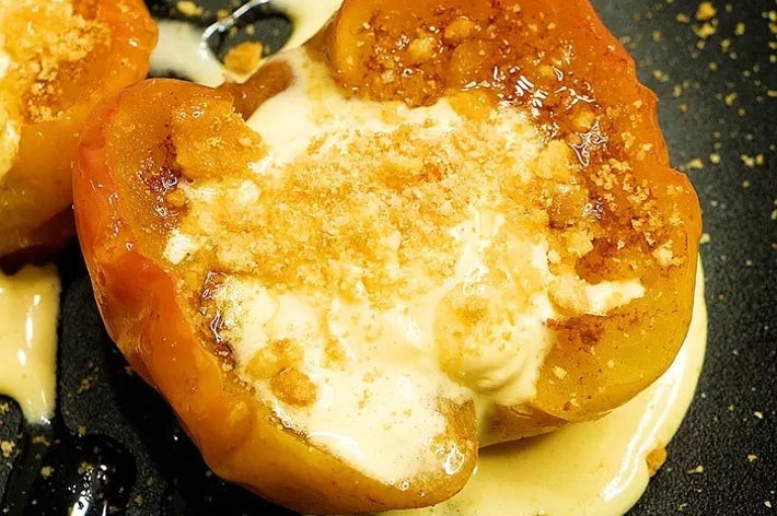 焼きトマトに溶けたチーズとパン粉が乗った料理。黒い皿に盛られています。