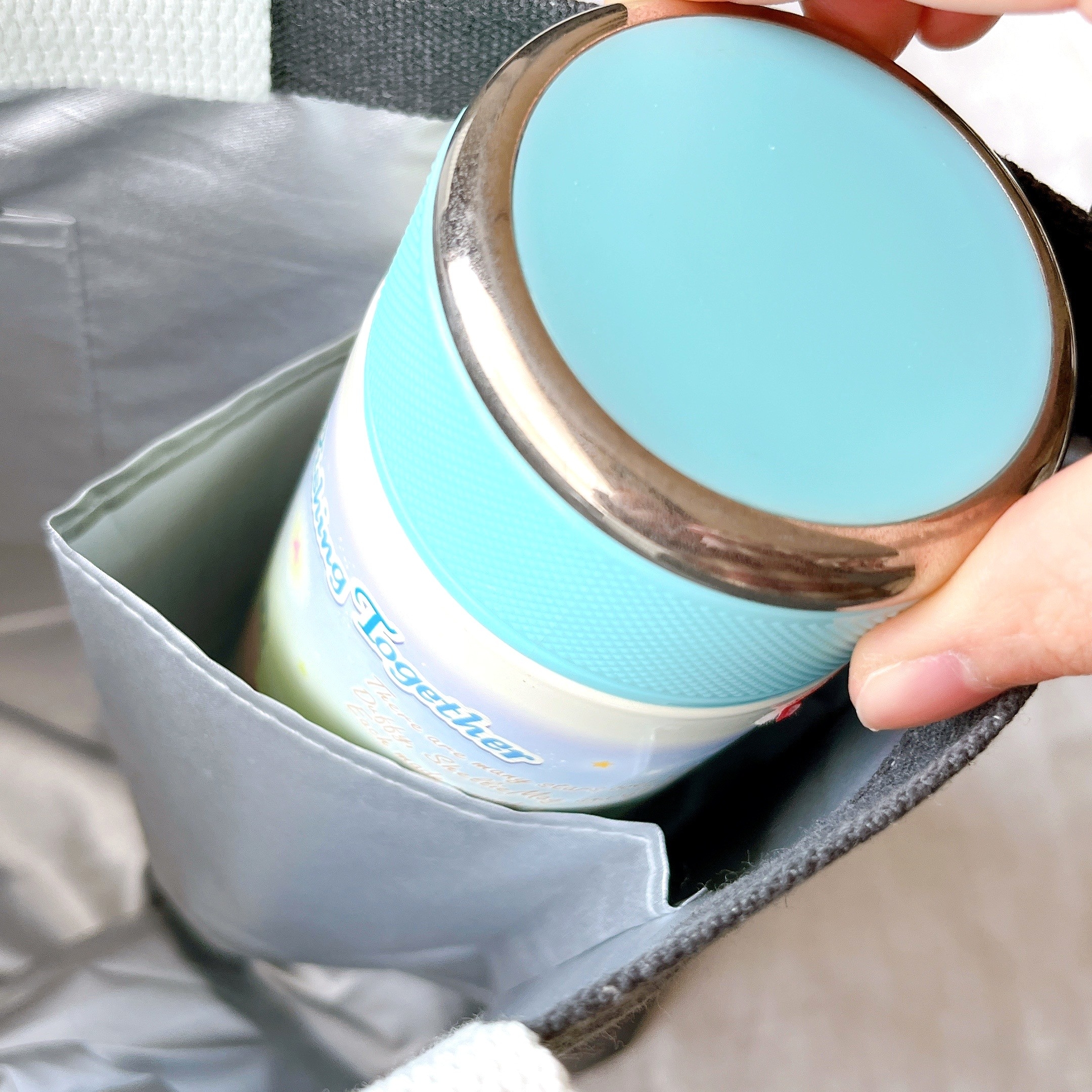 バッグに収まった缶とその上部を持つ手。